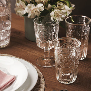 A clear glass with a Victorian-inspired design, featuring intricate embossed patterns and a wide mouth.