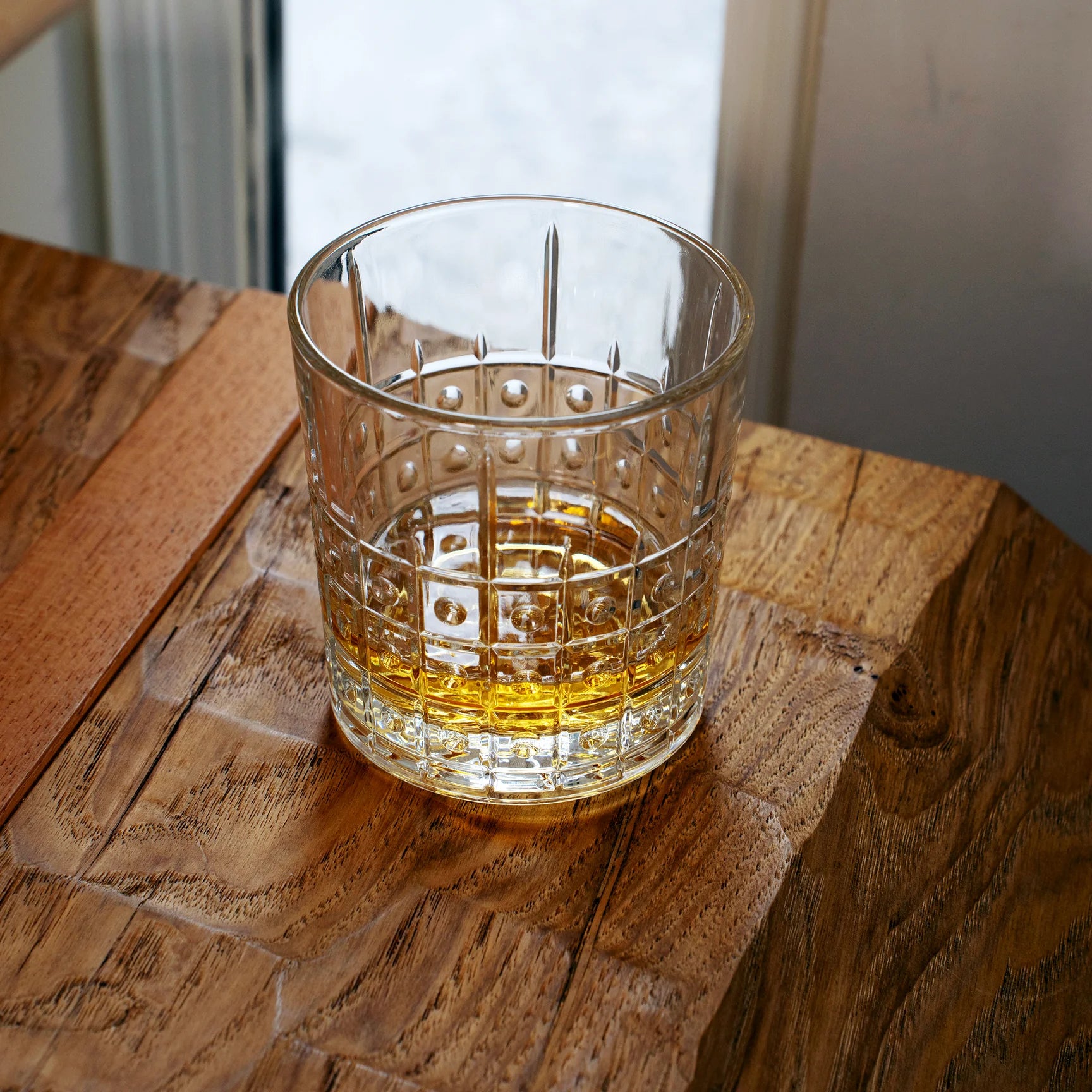 Este DOF glass filled with whisky standing on a wooden surface 
