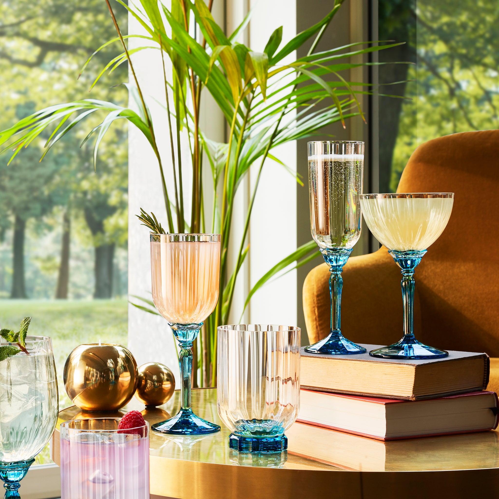 Florian glassware collection on a retro decorated table with books. Armchair, plants and a natural background. 