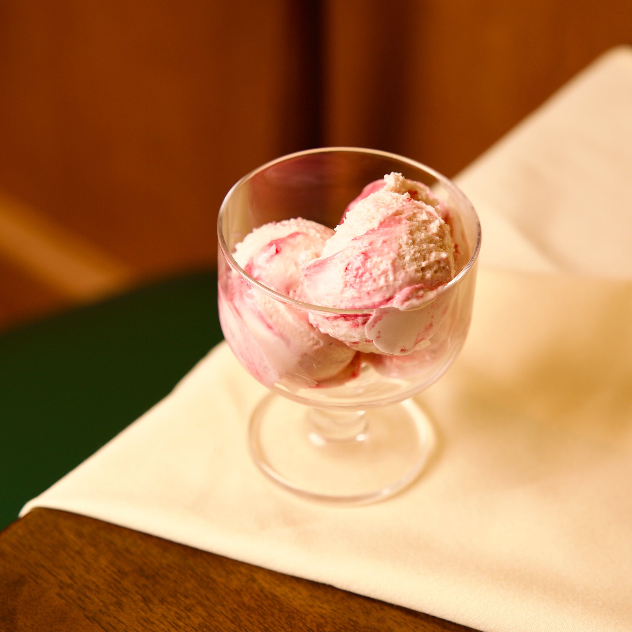 Hosteria dessert glass bowl with pink ice cream on a wooden surface