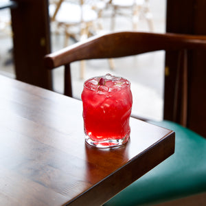 Red cocktail with ice in a Sorgente DOF glass on a wooden table